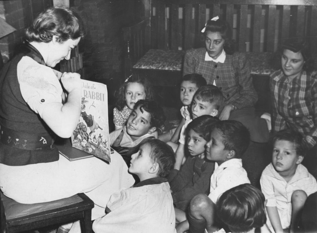 Miniature of Ruth Roth, director of Hull-House morning play group, reads "The Tale of Rabbit" to a group of children