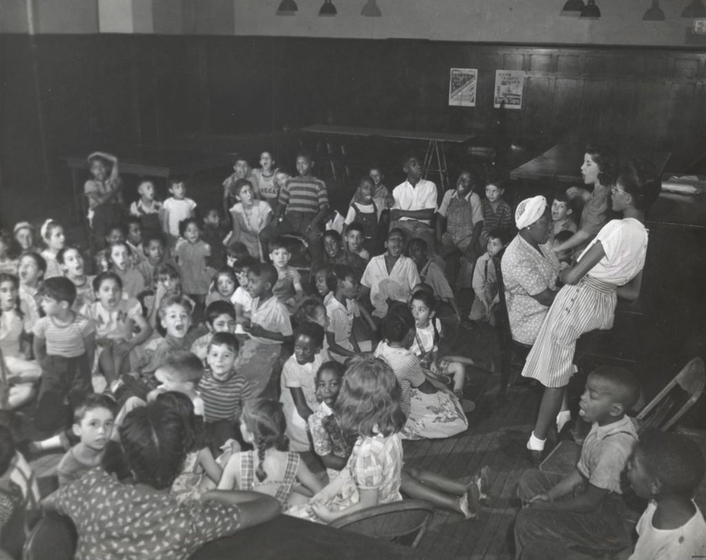 Children singing in a large room at Hull-House