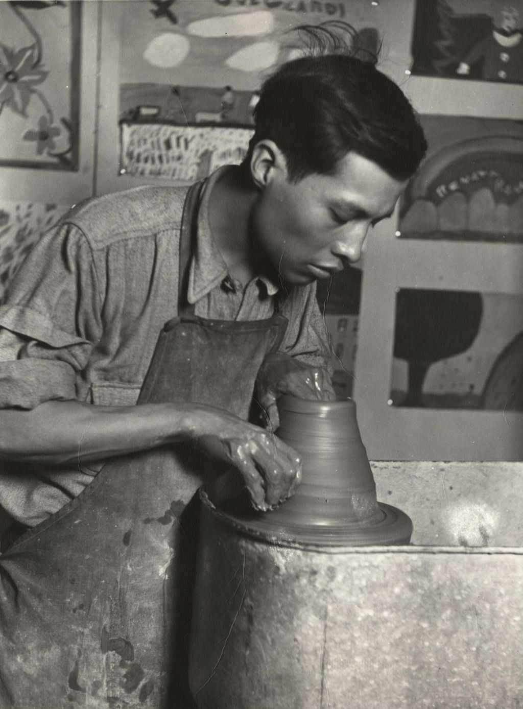 Artist Jesús Torres throwing a clay pot at a potter's wheel in a Hull-House art classroom