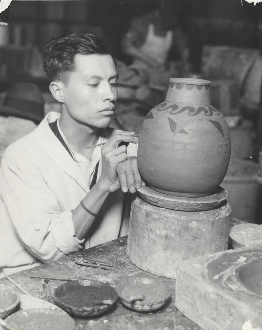 Miniature of Artist Jesús Torres hand-decorating a clay pot at Hull-House Kilns