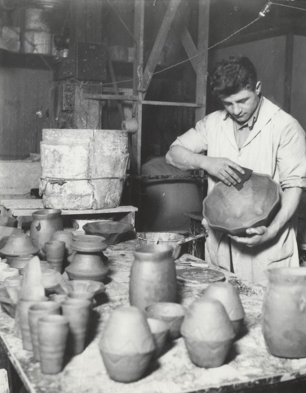Miniature of Foreman of Hull-House Kilns Nick Fosco polishing a ceramic bowl