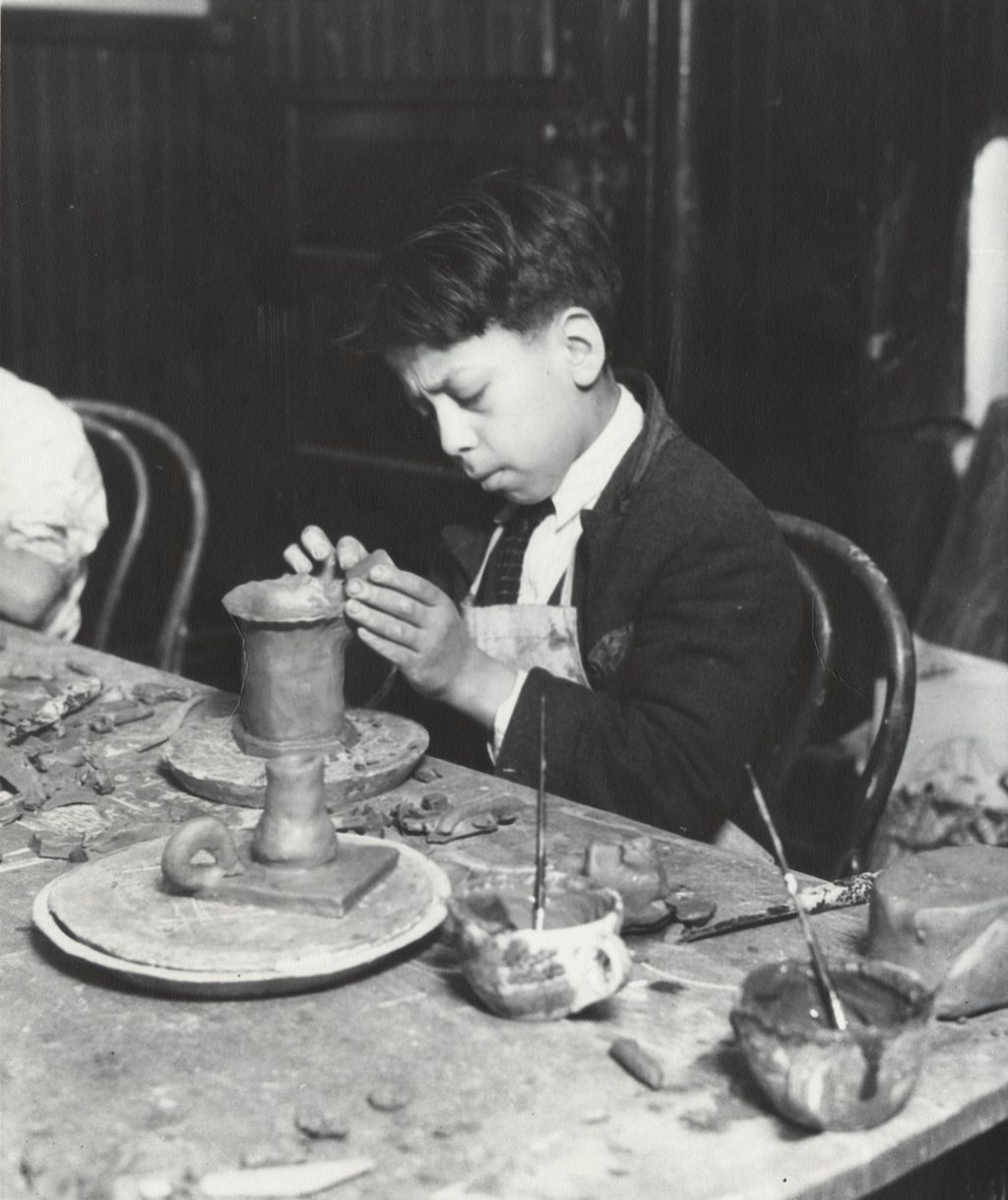 Miniature of Boy in Hull-House ceramics class putting finishing touches on clay vase