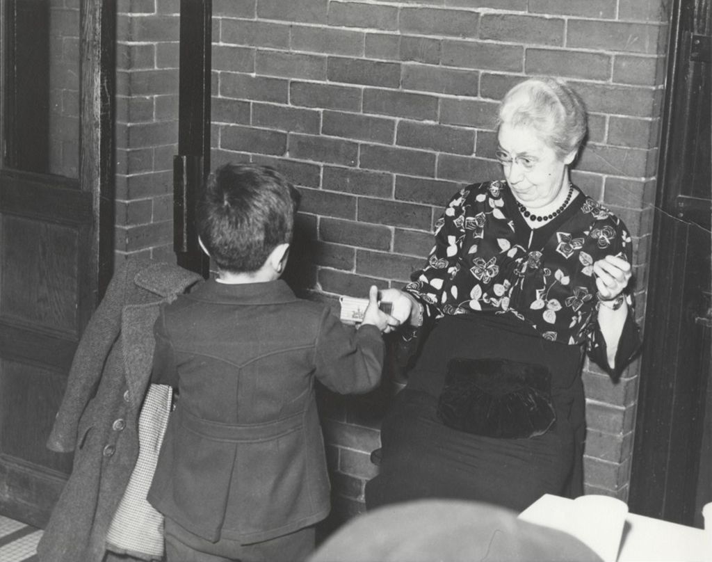 Hull-House Music School director Gertrude Smith handing a holiday box to boy