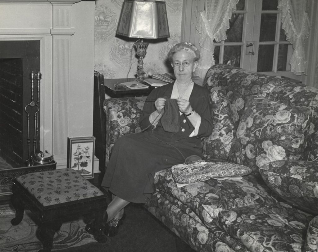 Miniature of Louise de Koven Bowen knitting while sitting on a couch in her cottage at Bowen Country Club