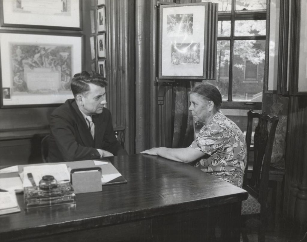 Miniature of Hull-House Head Resident Russell W. Ballard at his desk with woman from neighborhood