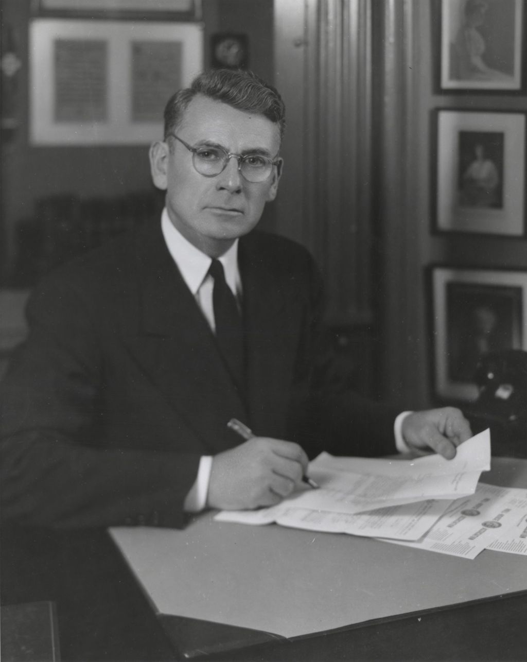 Hull-House Head Resident Russell W. Ballard signing papers at his desk