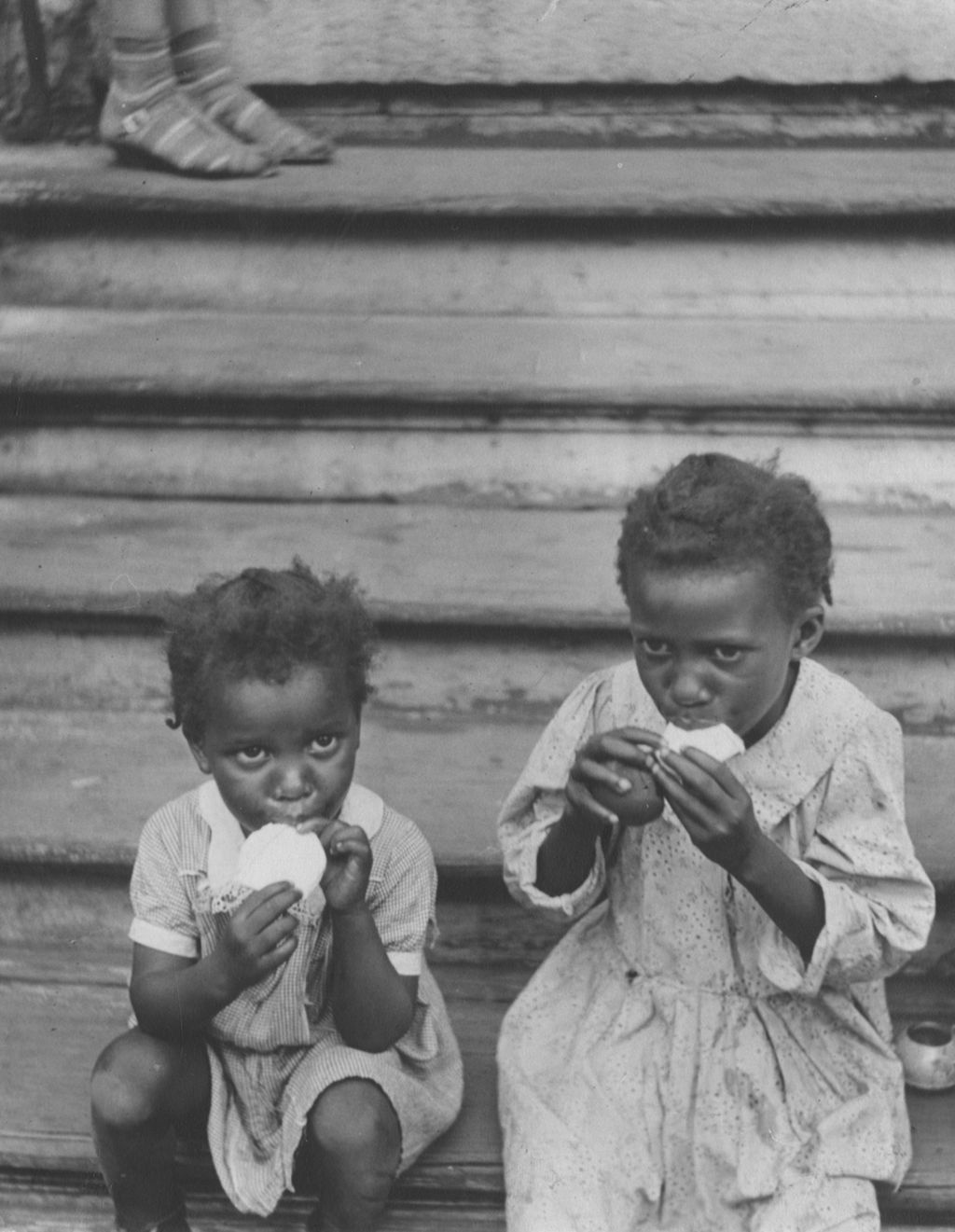 Two girls sitting on steps, having a snack