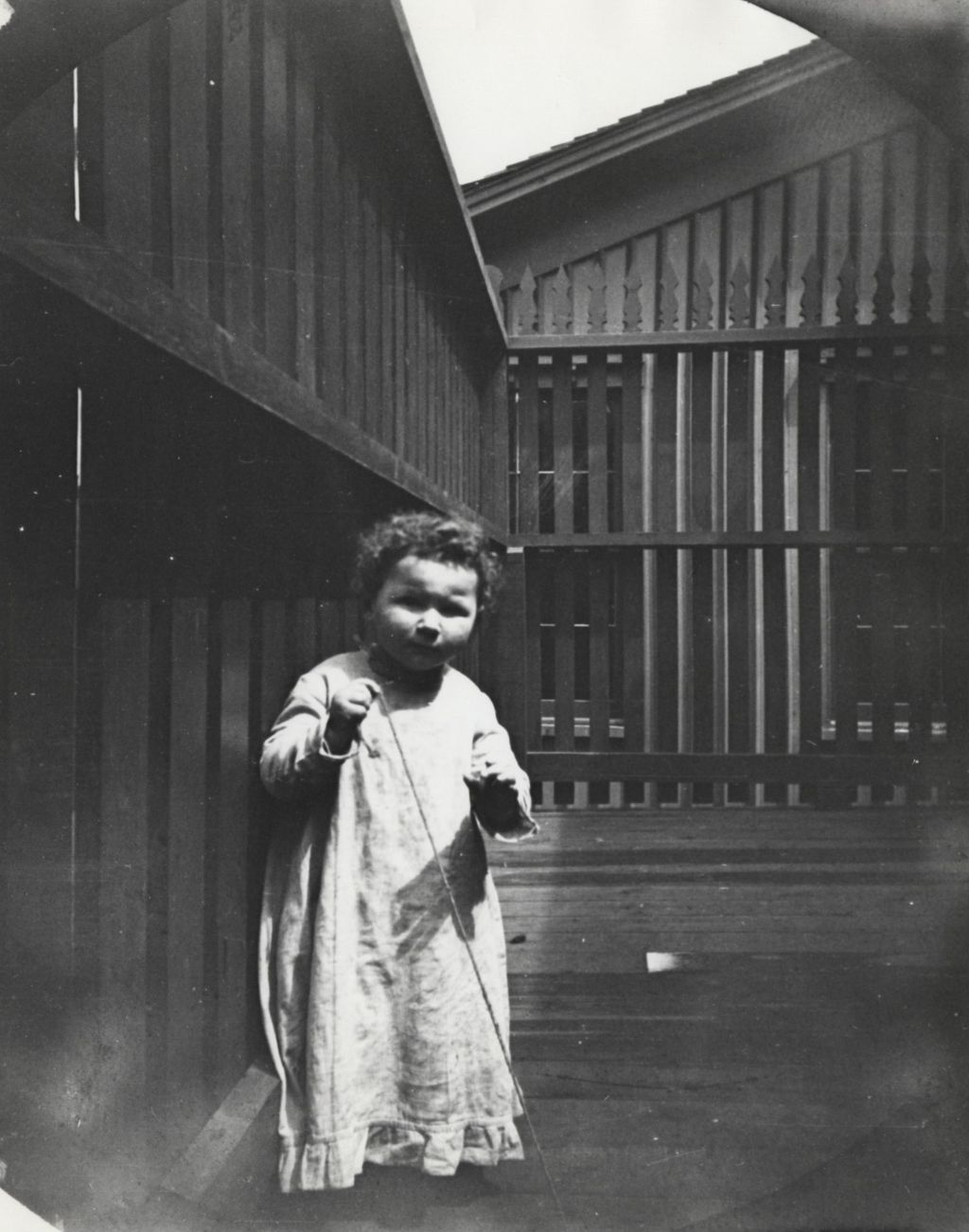 Miniature of Young child standing on a deck holding a thin rope in neighborhood near Hull-House