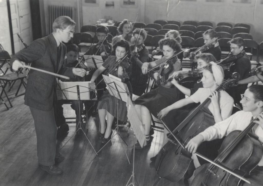 Young man conducting group of string players