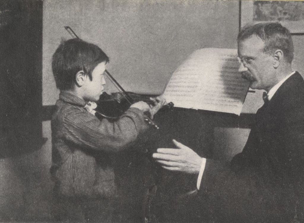 Man giving a violin lesson to boy at Hull-House Music School