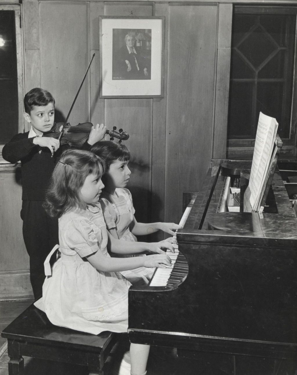 Two girls playing piano and boy playing violin at Hull-House Music School