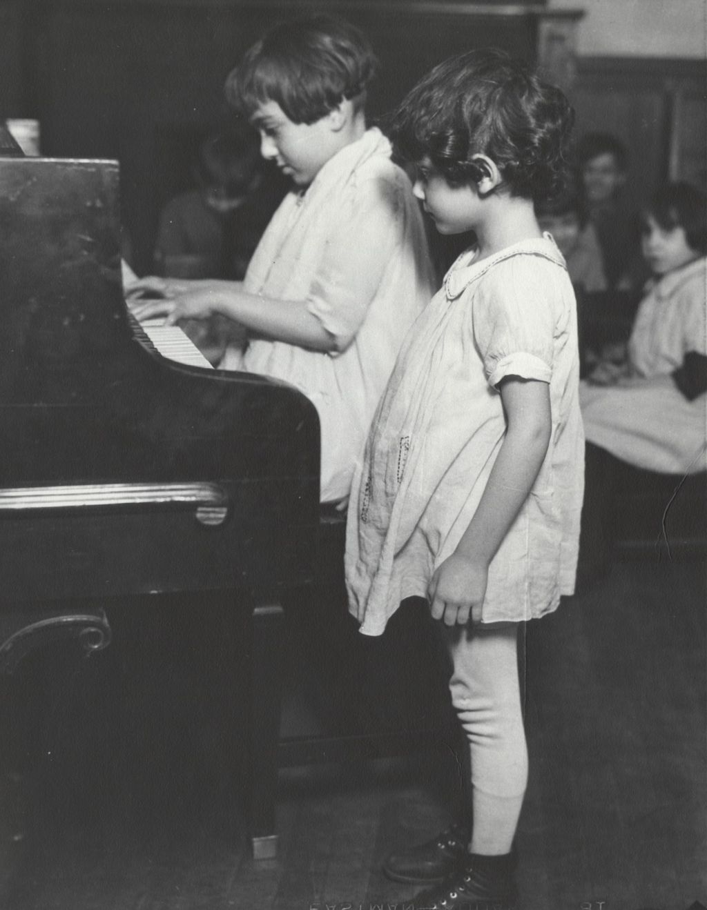 Girl playing piano while another girl watches