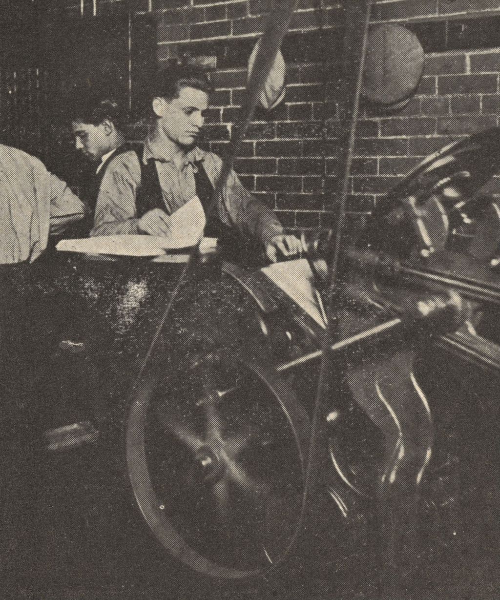 Young man working a printing machine at Hull-House Industrial Arts Shop