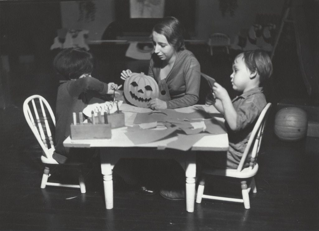 Hull-House nursery school practice teacher doing Halloween crafts with children