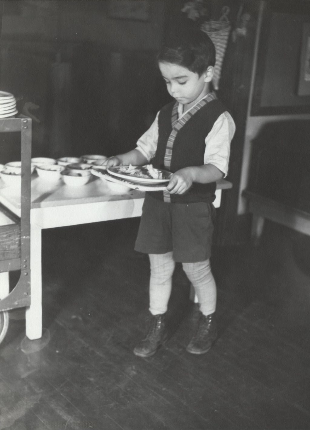 Boy holds tray with plate of food at Hull-House nursery school