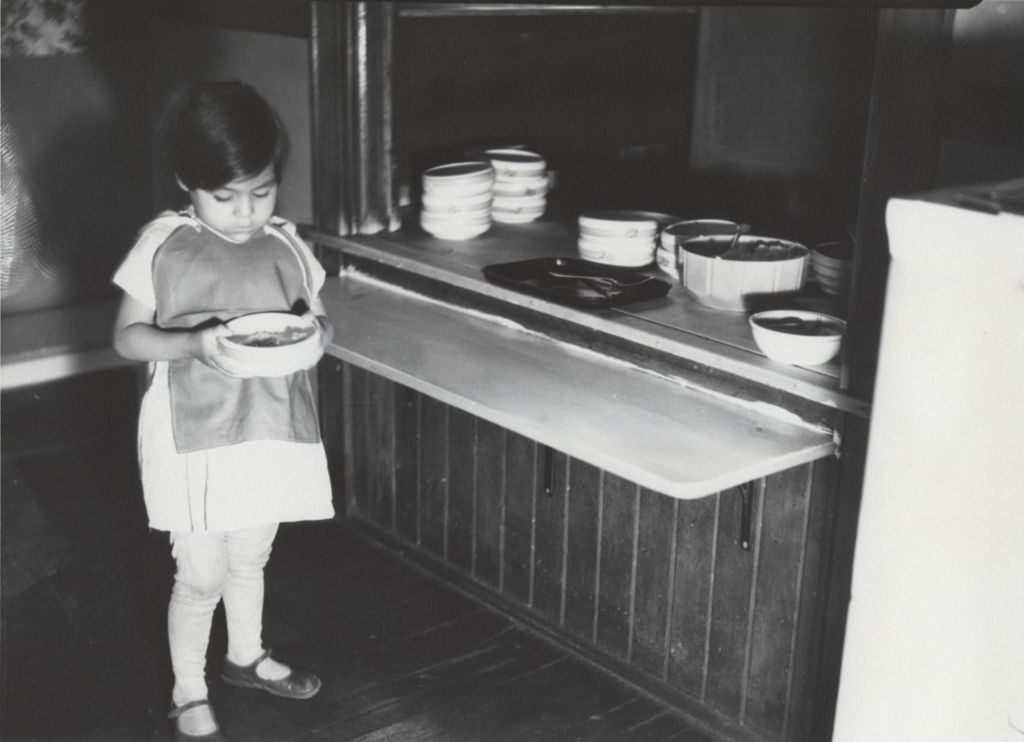 Miniature of Young girl holding bowl of food at a meal counter