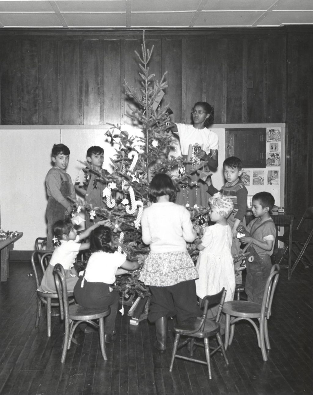 Teacher Marie Turner and eight children decorate a Christmas tree