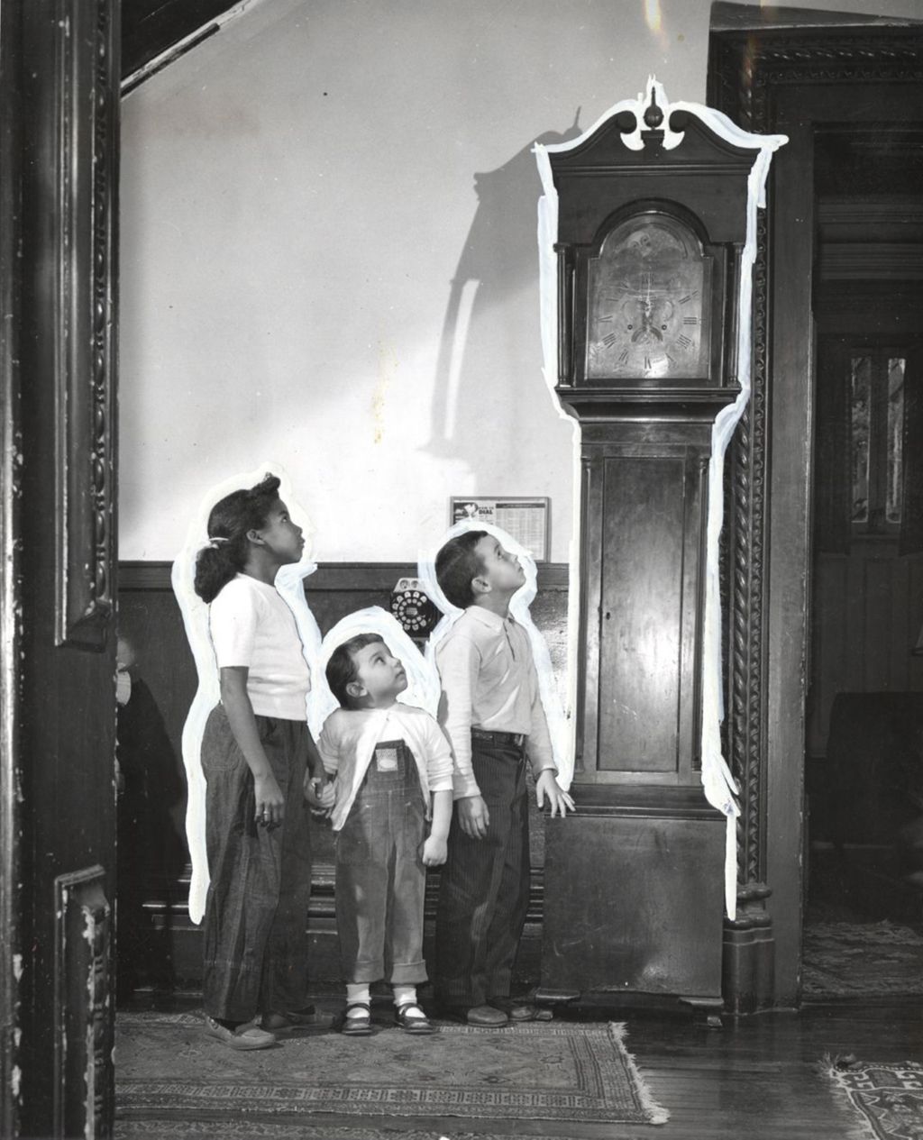 Three children looking up at grandfather clock