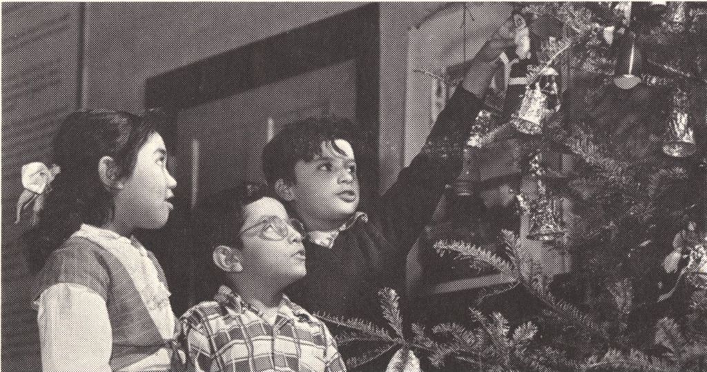 Miniature of A girl and two boys help decorate a Christmas tree at Hull-House