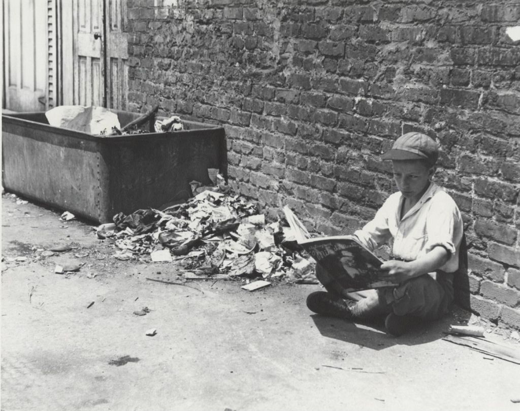 Boy reading picture book in alley near Hull-House