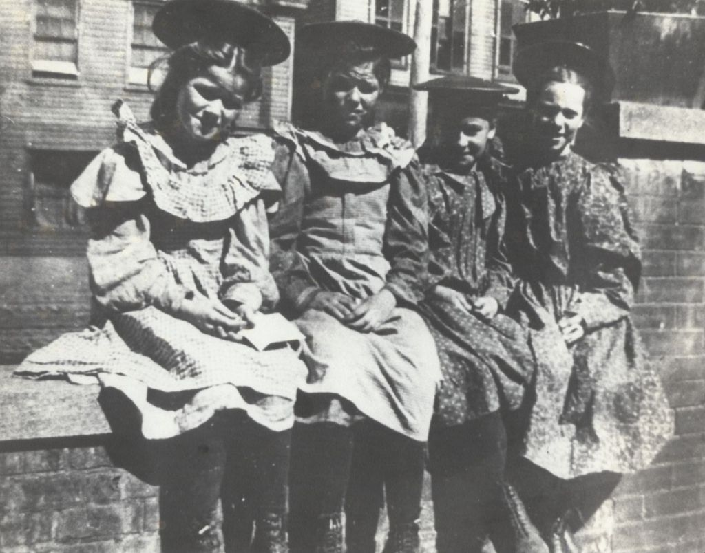 Miniature of Four girls sitting on a brick wall