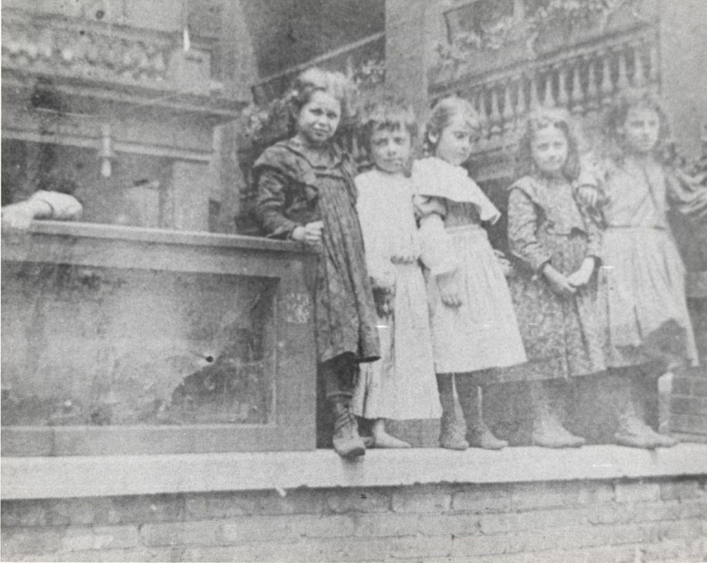 Miniature of Five girls standing on short brick wall, with boy nearby