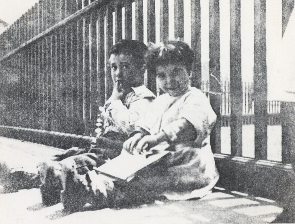 Miniature of Two children sitting against the fence outside of Hull-House