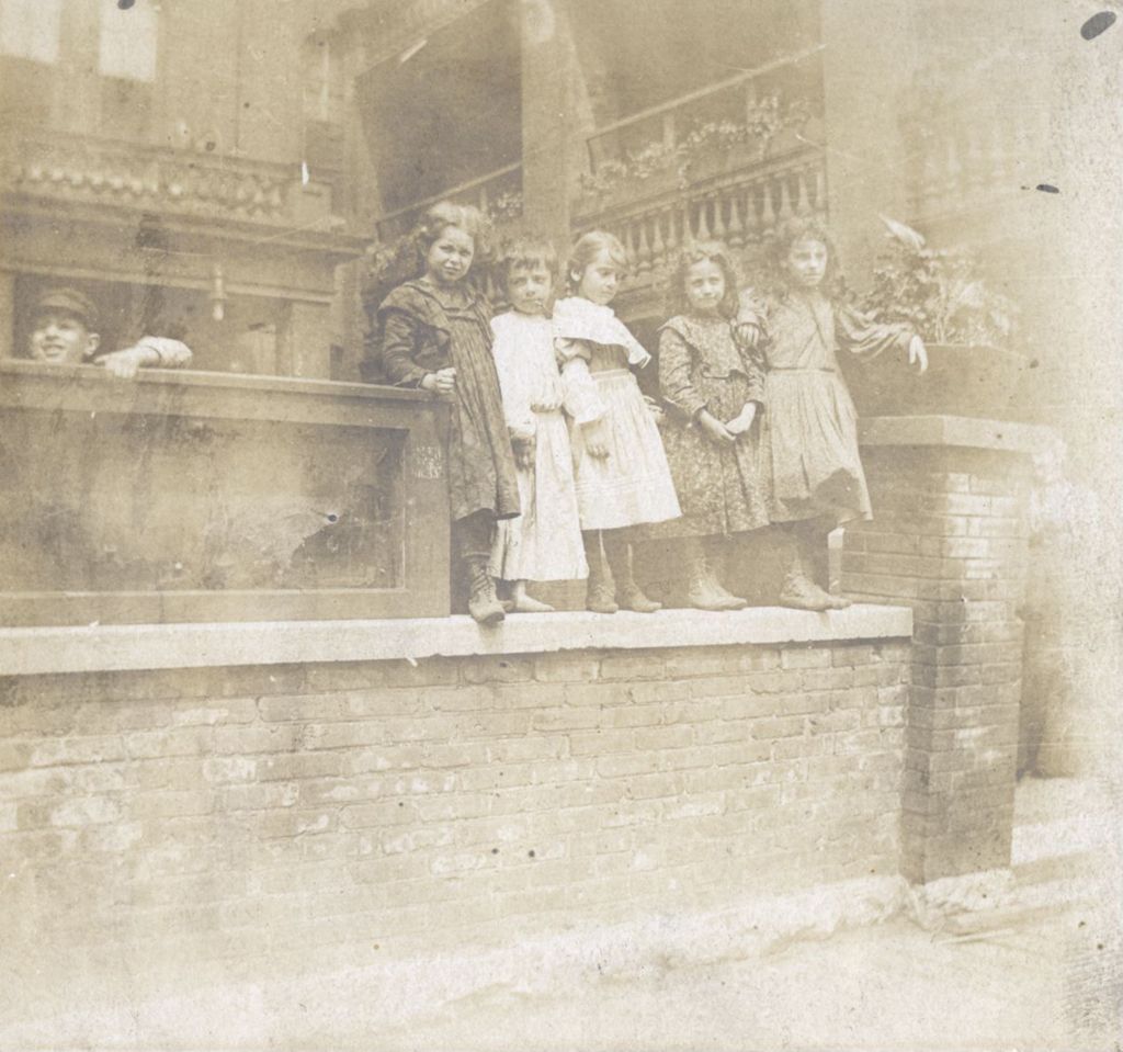 Miniature of Five girls standing on short brick wall, with boy nearby
