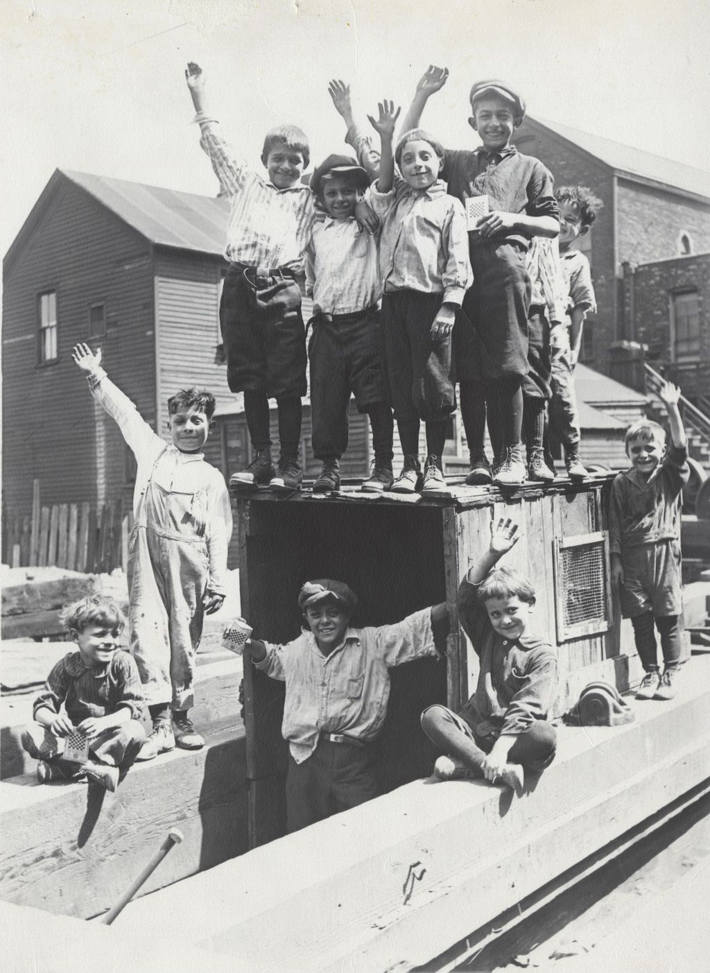 Eleven boys posing on and around a wood club house in the Hull-House neighborhood
