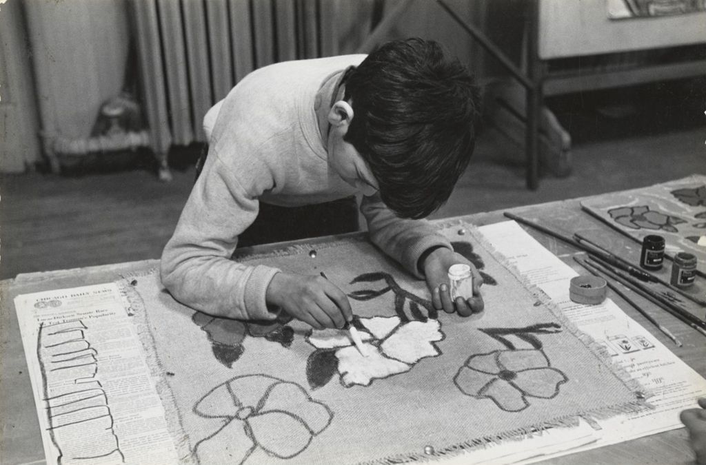 Boy painting flowers on fabric in art class