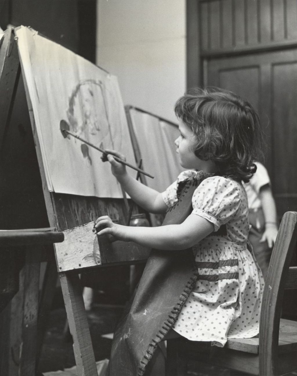 Young girl painting at easel in art class
