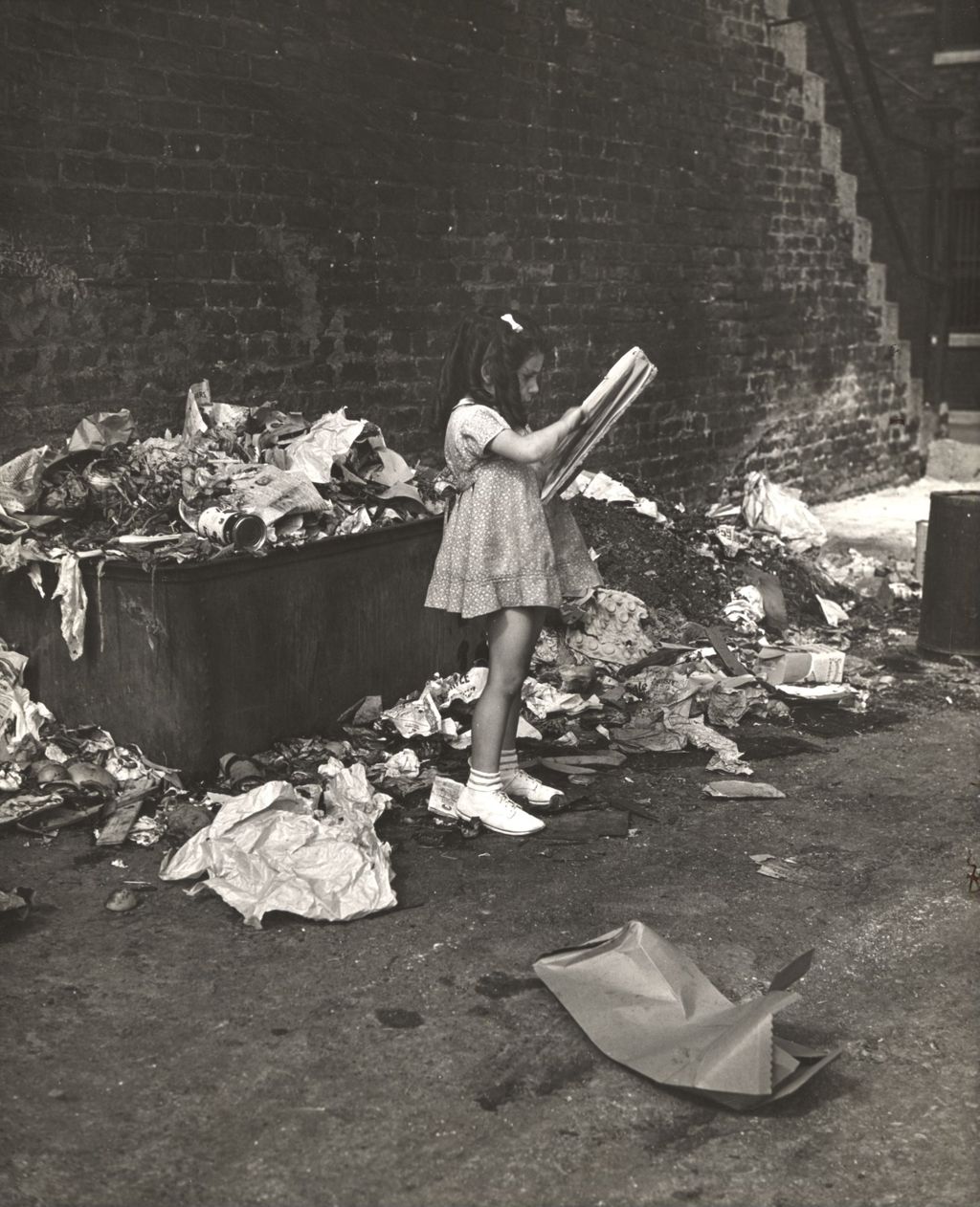 Young girl sketching on pad while standing in a garbage-strewn alley near Hull-House