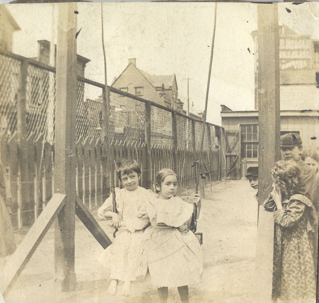 Miniature of Two girls in dresses swinging in the Hull-House playground with the Smith building visible in background