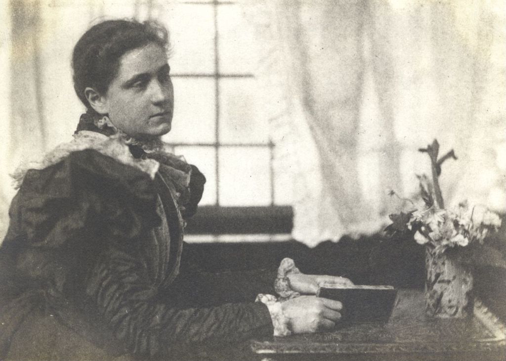 Miniature of 3/4 seated portrait of Jane Addams holding a book and seated at a table or desk taken on visit to London with Mary Rozet Smith