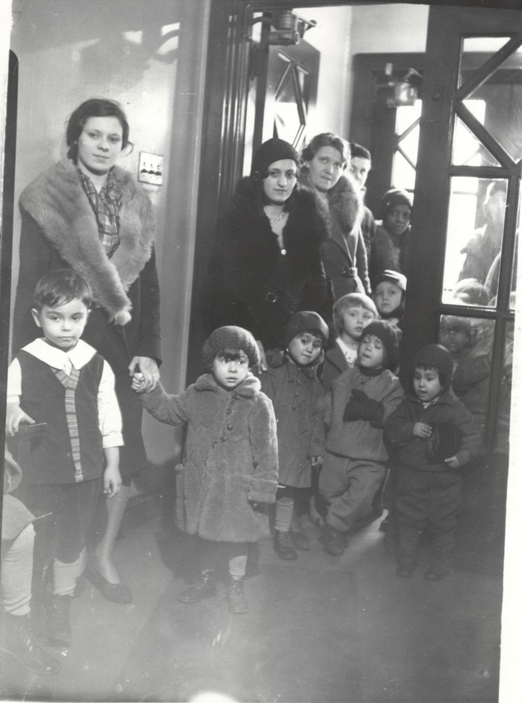Miniature of Mothers and children wearing coats and waiting in a Hull-House doorway